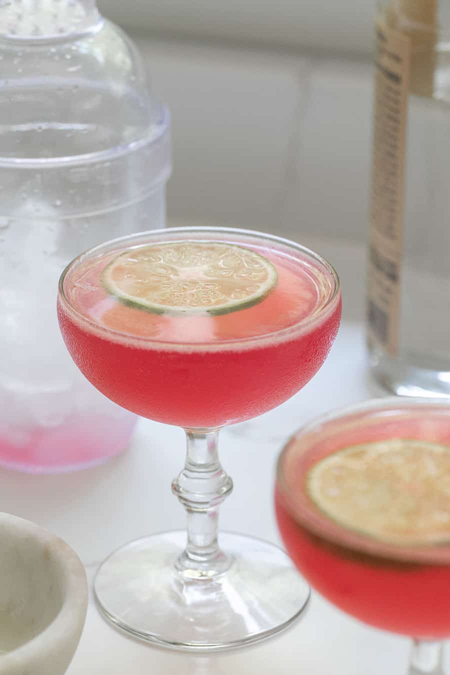 Cosmopolitan cocktail with a lime wheel in a coupe glass.