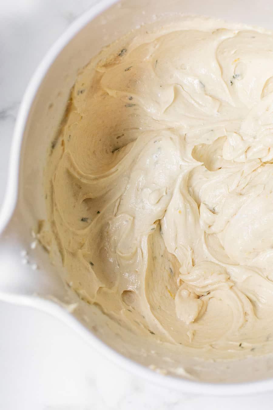 Loaf cake batter with rosemary and lemon in a mixing bowl. 