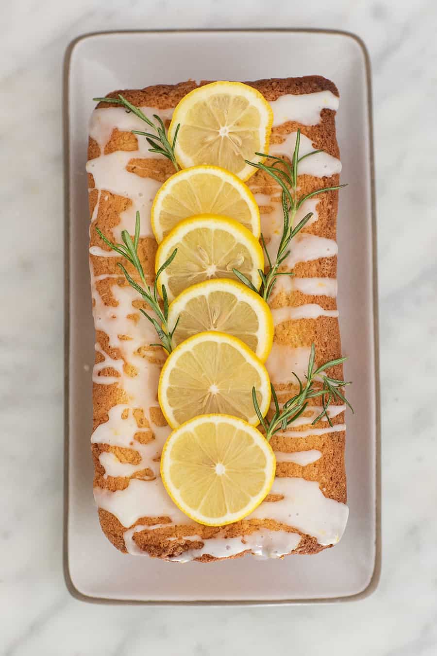 Lemon loaf cake with lemon slices and rosemary.