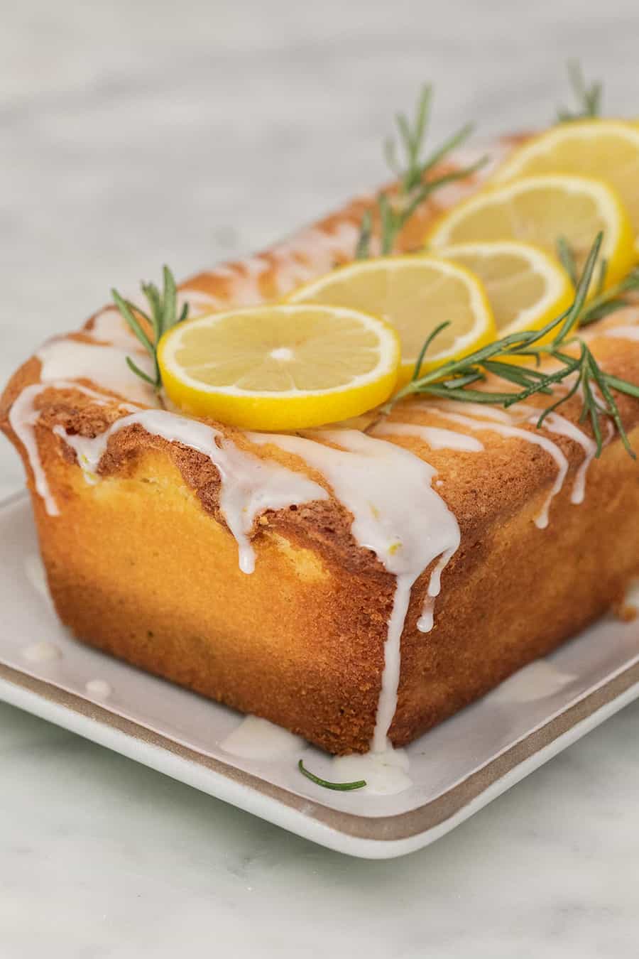 rosemary lemon loaf cake recipe with glaze over the top.