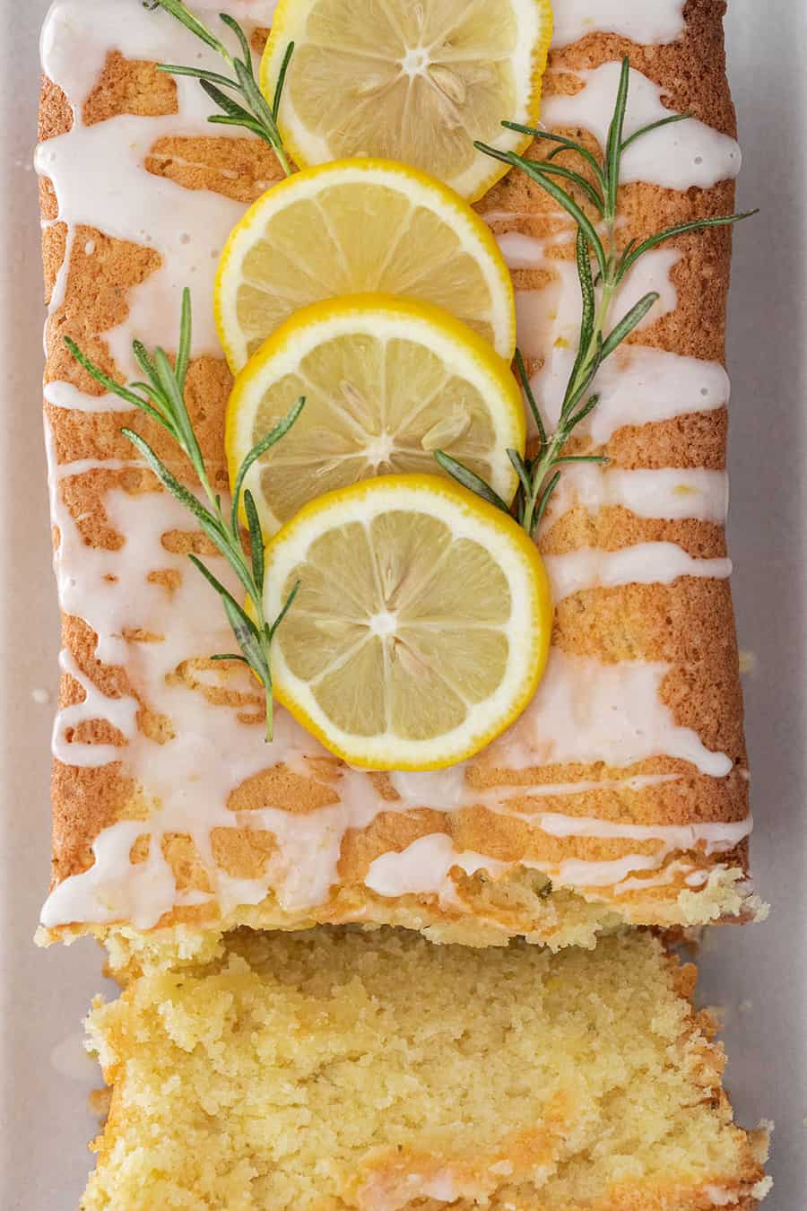 Rosemary Lemon Loaf cake cut with sliced lemon and fresh rosemary.