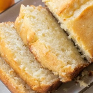 Super moist lemon loaf cake with buttery lemon flavor and texture sliced on a plate.