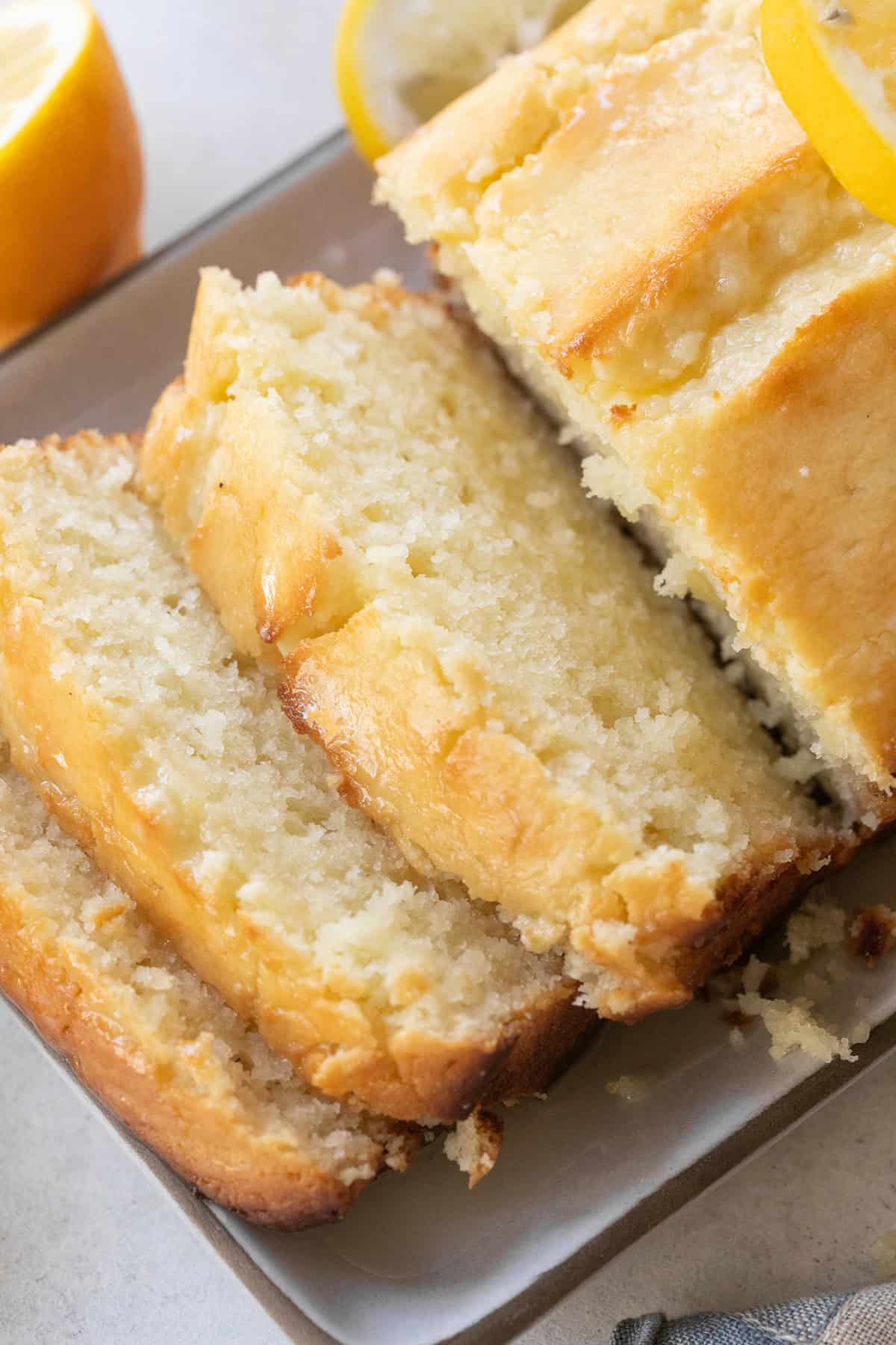Super moist lemon loaf cake with buttery lemon flavor and texture sliced on a plate.