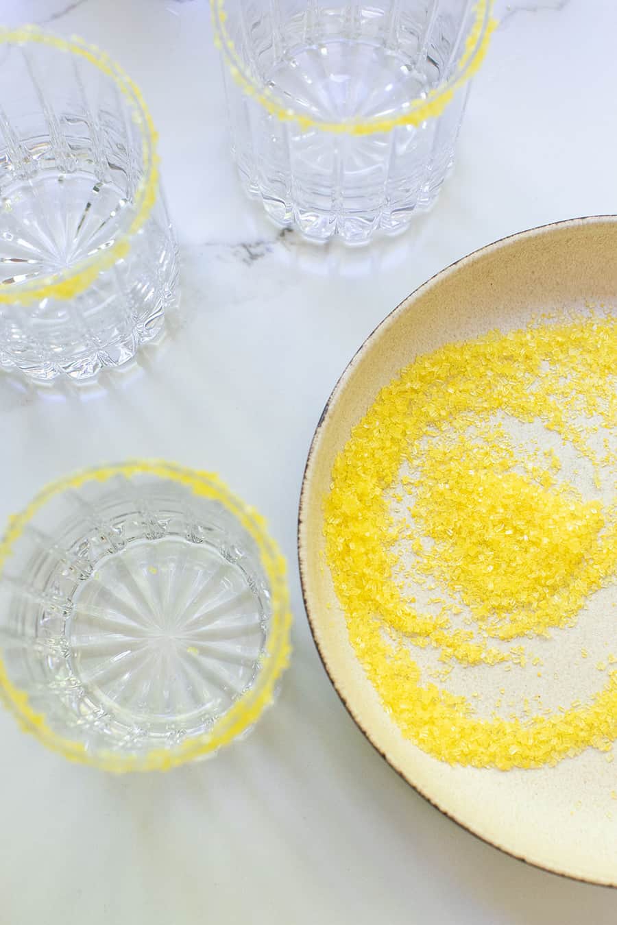 Yellow sugar in a plate with rimmed glasses.