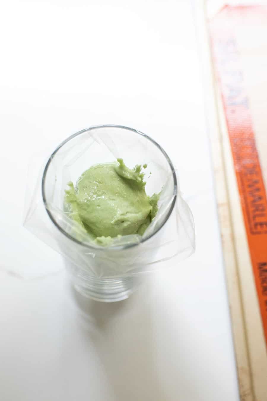 Green macaron batter in a cup.
