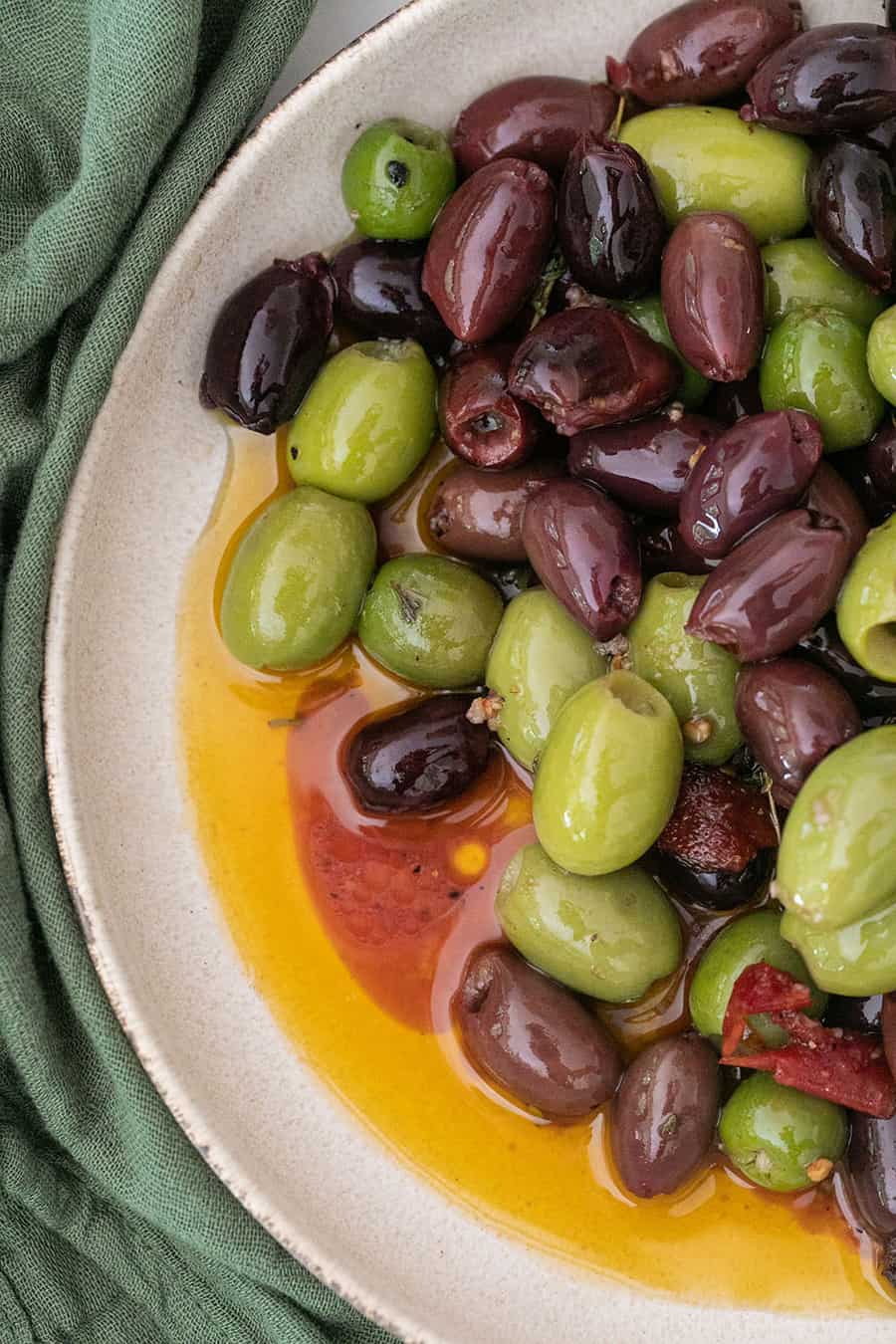 marinated green and kalamata olives in a bowl with sauce.