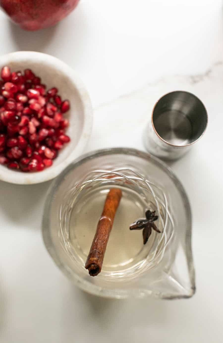 Cinnamon simple syrup with a cocktail jigger and fresh pomegranates. 