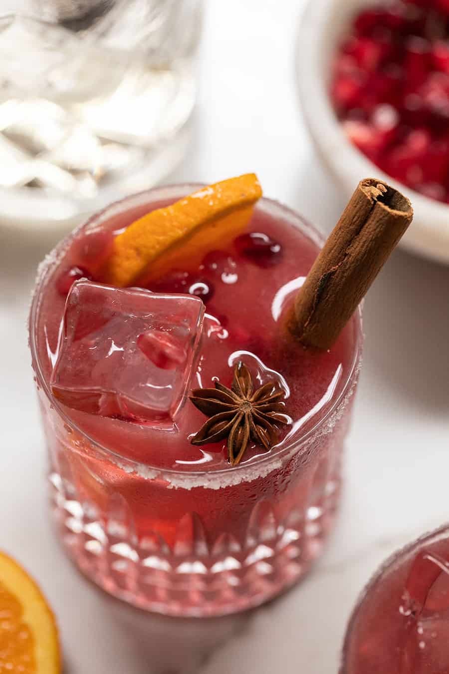 Red pomegranate margaritas with cinnamon stick, orange slice and star anise. 