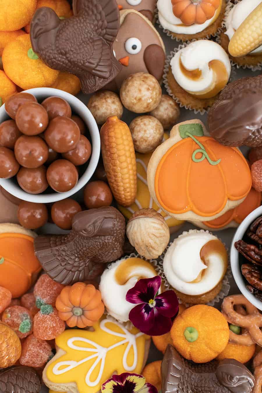 Chocolate covered turkey, cupcakes, pumpkins and cookies on a platter.