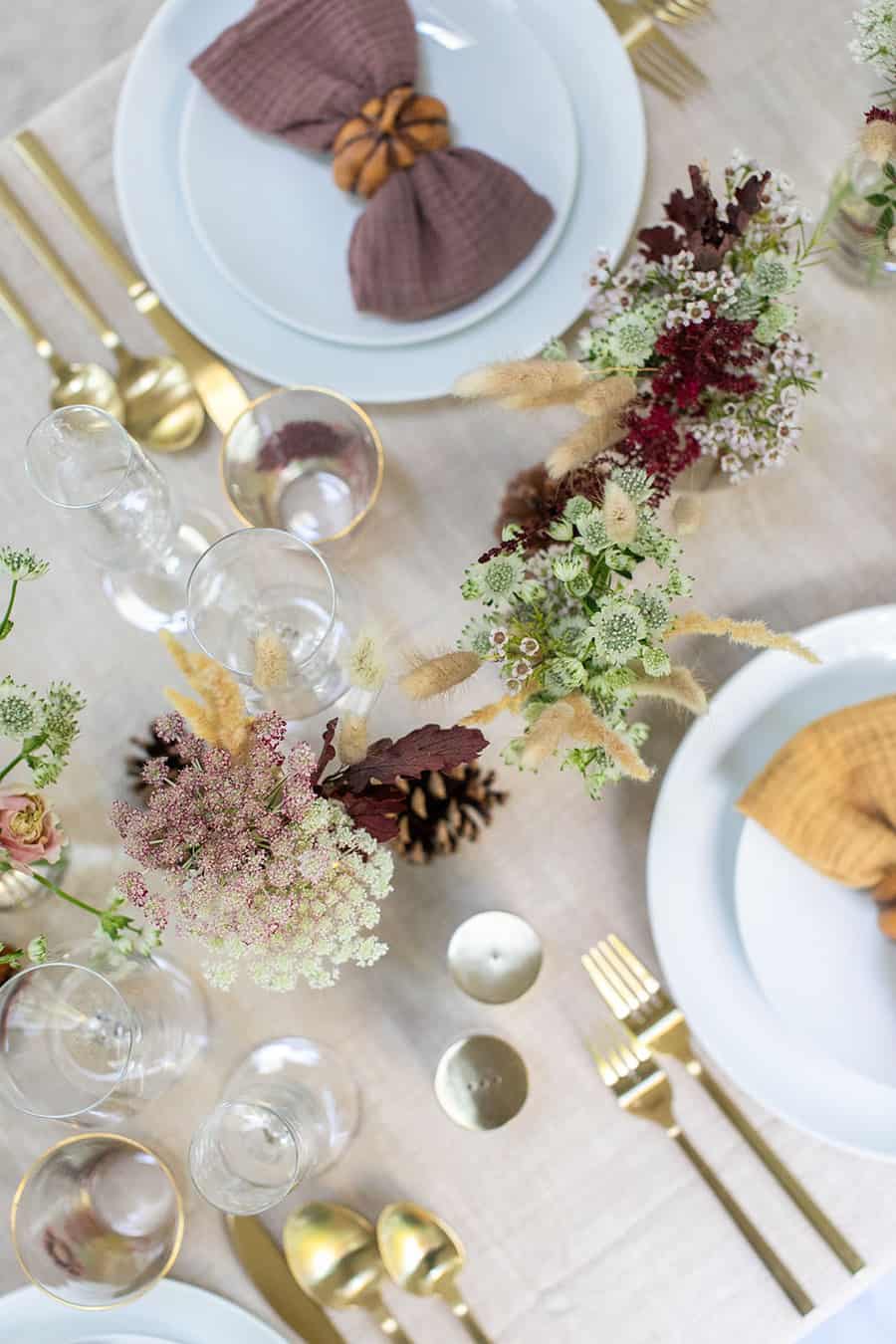 Flowers, fold flatware and pretty napkins for a Thanksgiving table setting.