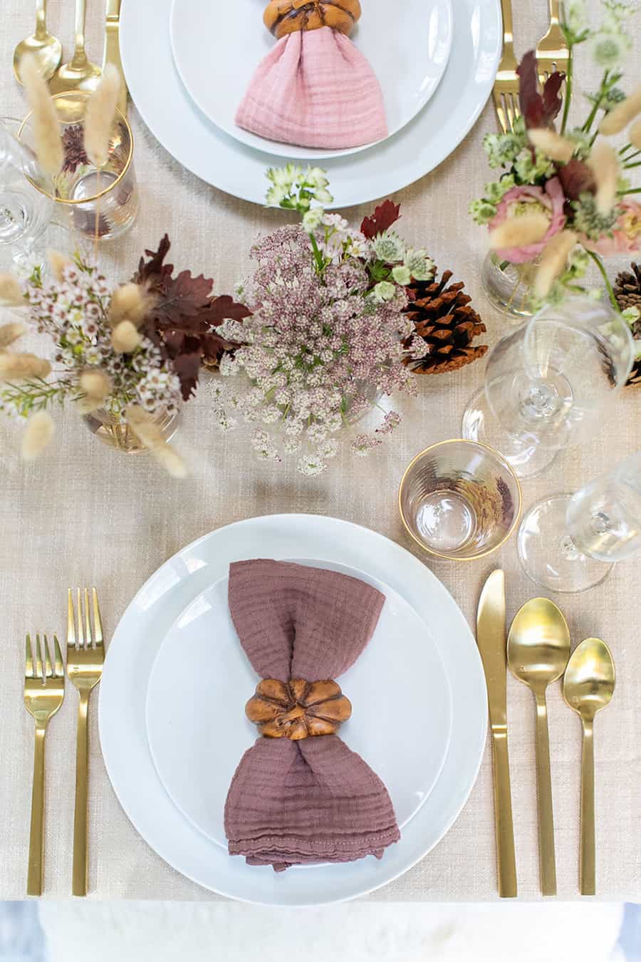 Simple fall Thanksgiving table setting, white plates, gold flatware and pretty flowers.