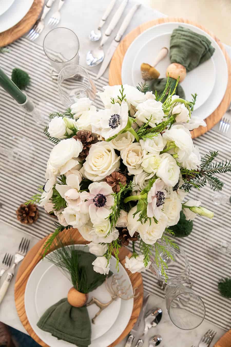 Christmas flower arrangement on a table with striped linen table runner.