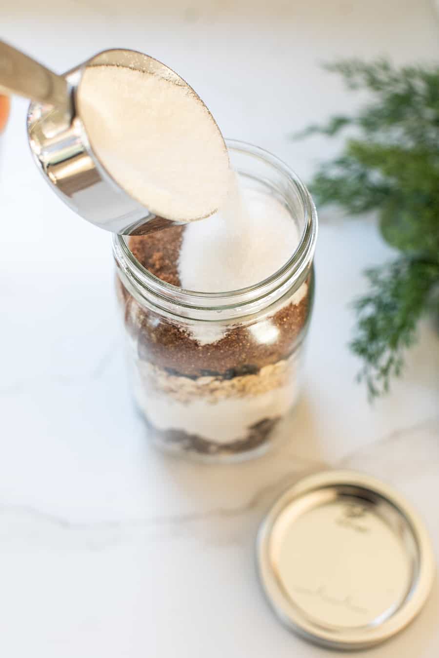 Pouring sugar to cookie mix in a jar