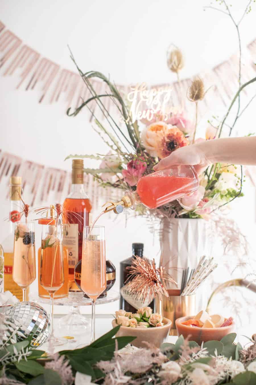 Pouring in juice to a glass of Champagne for a New Year's Eve Champagne Bar