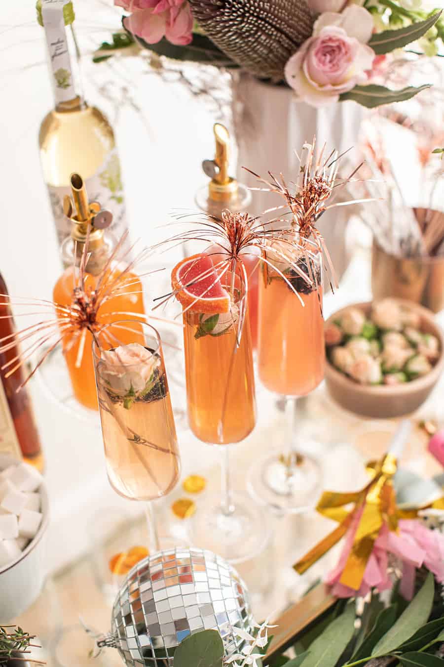 Festive Champagne cocktails for New Year's Eve with flowers, sparklers and berries.