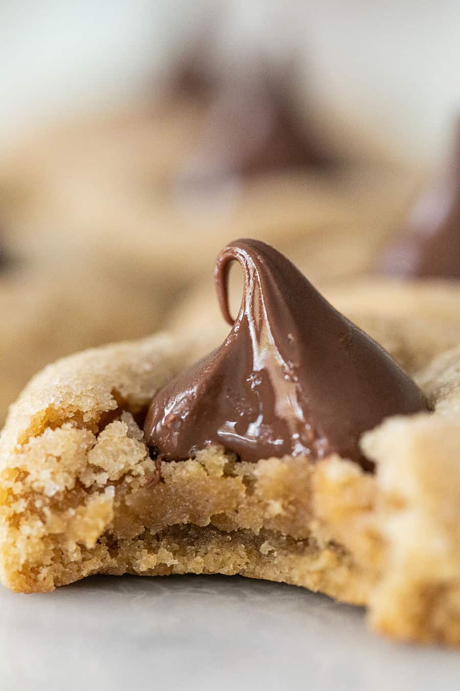 Bite taken out of a peanut butter blossom cookie with a Hershey's Kiss.