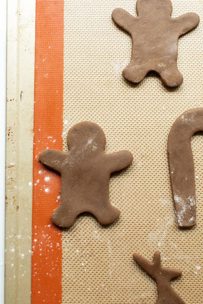 Cut gingerbread men on a parchment-lined baking sheet before baking.