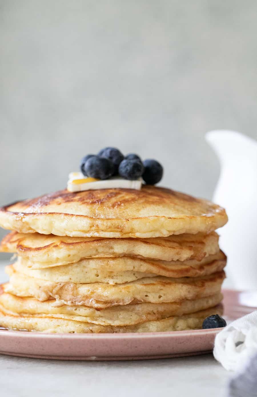 Stack of fluffy pancakes with blueberries, maple syrup and butter.