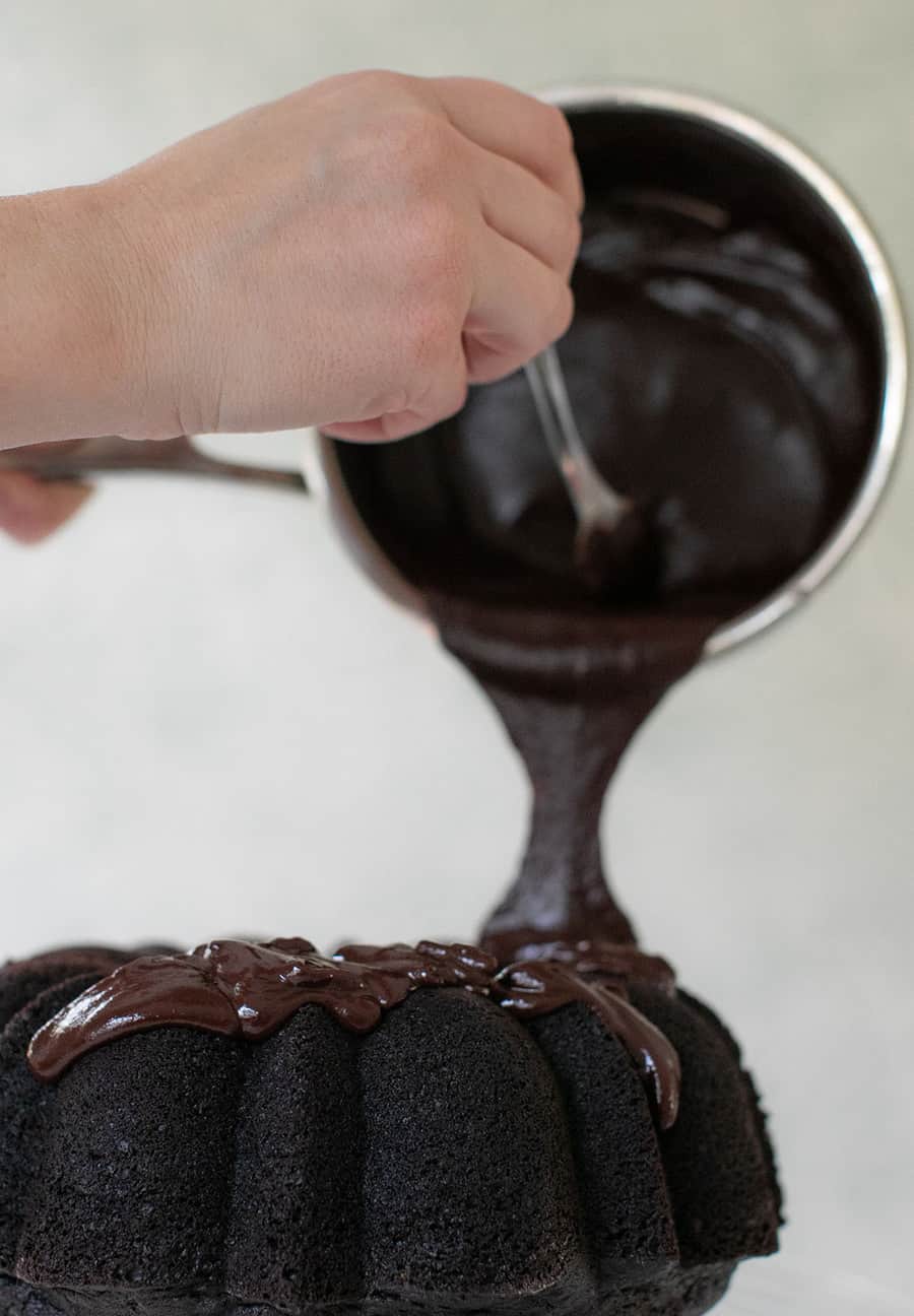 Pouring chocolate ganache all over a bundt cake