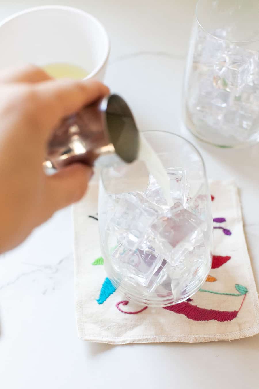 Pouring lime juice into a glass with ice.