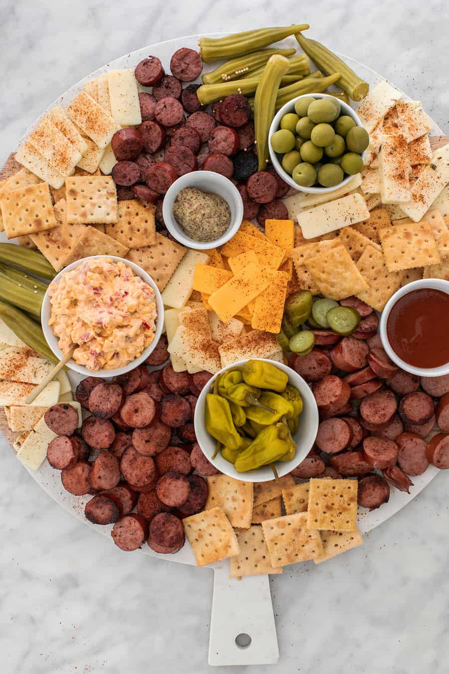 Cheese and meat platter with crackers, sausage, cheese, pimento cheese, pickles and olives.