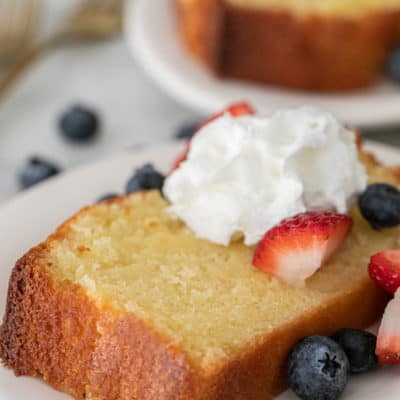 Slice of old-fashioned pound cake with whipped cream and berries.