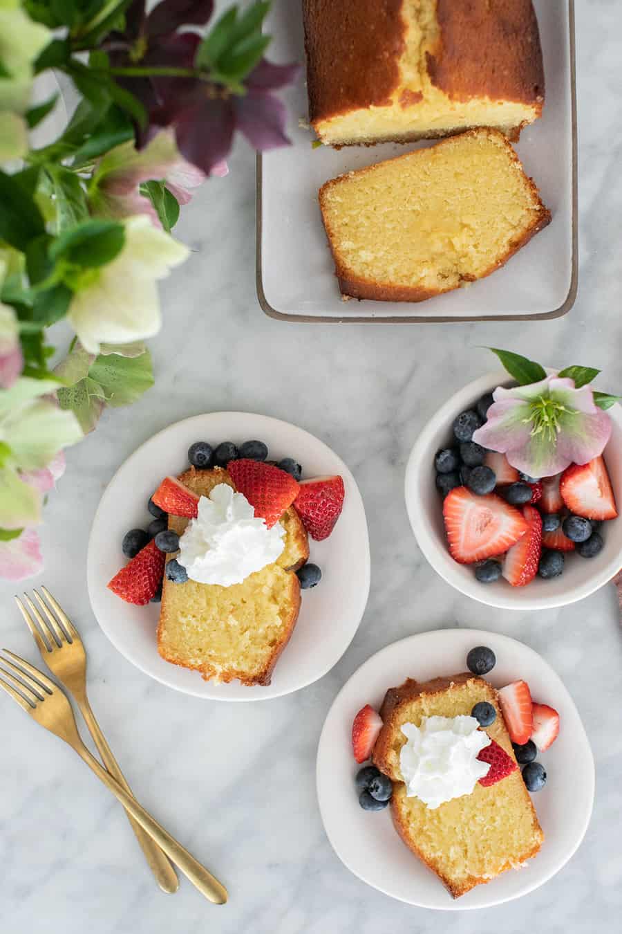 Pound cake on plate sliced with whipped cream and strawberries 