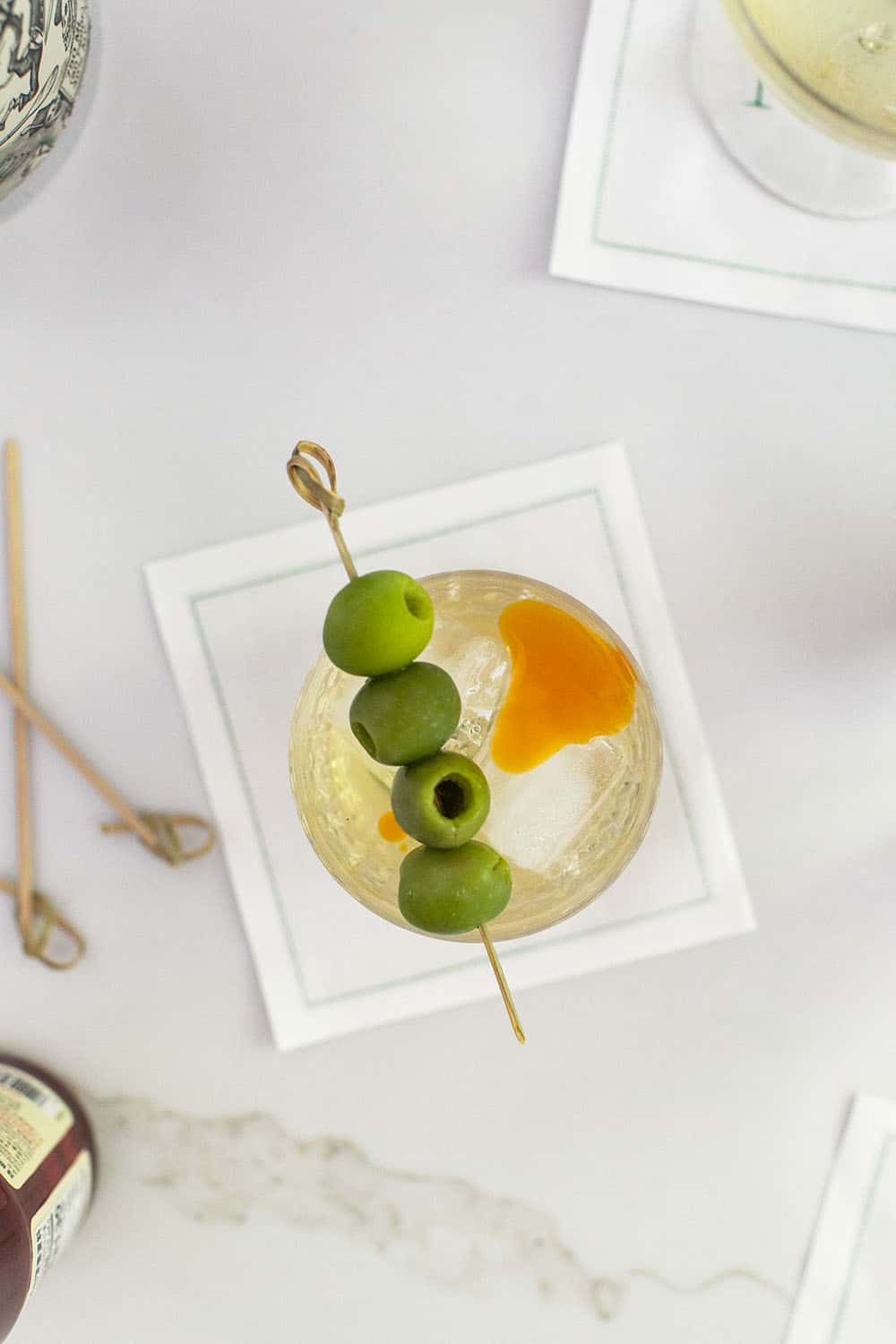 Dirty martini with 4 green olives and a dash of chili oil over the top.