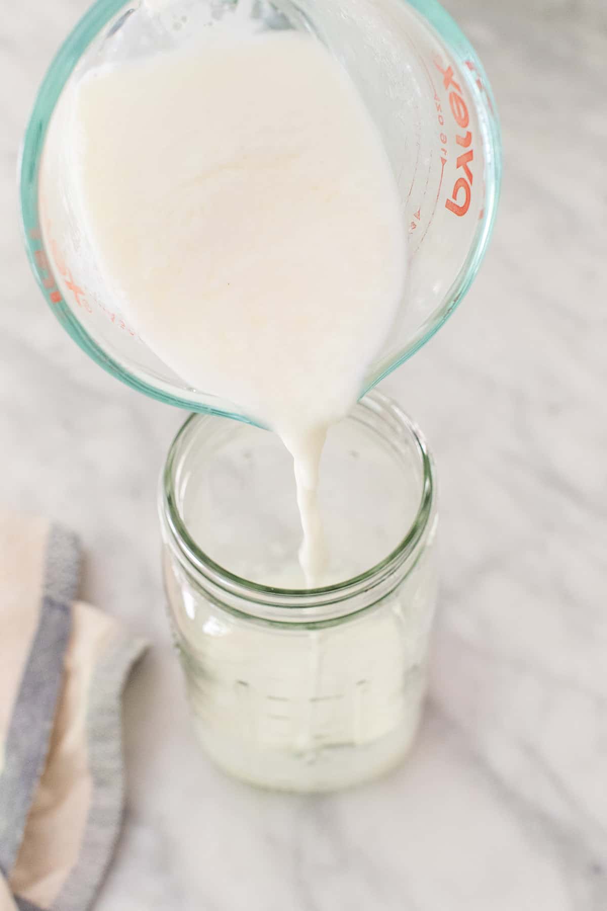 Pouring buttermilk into a jar 