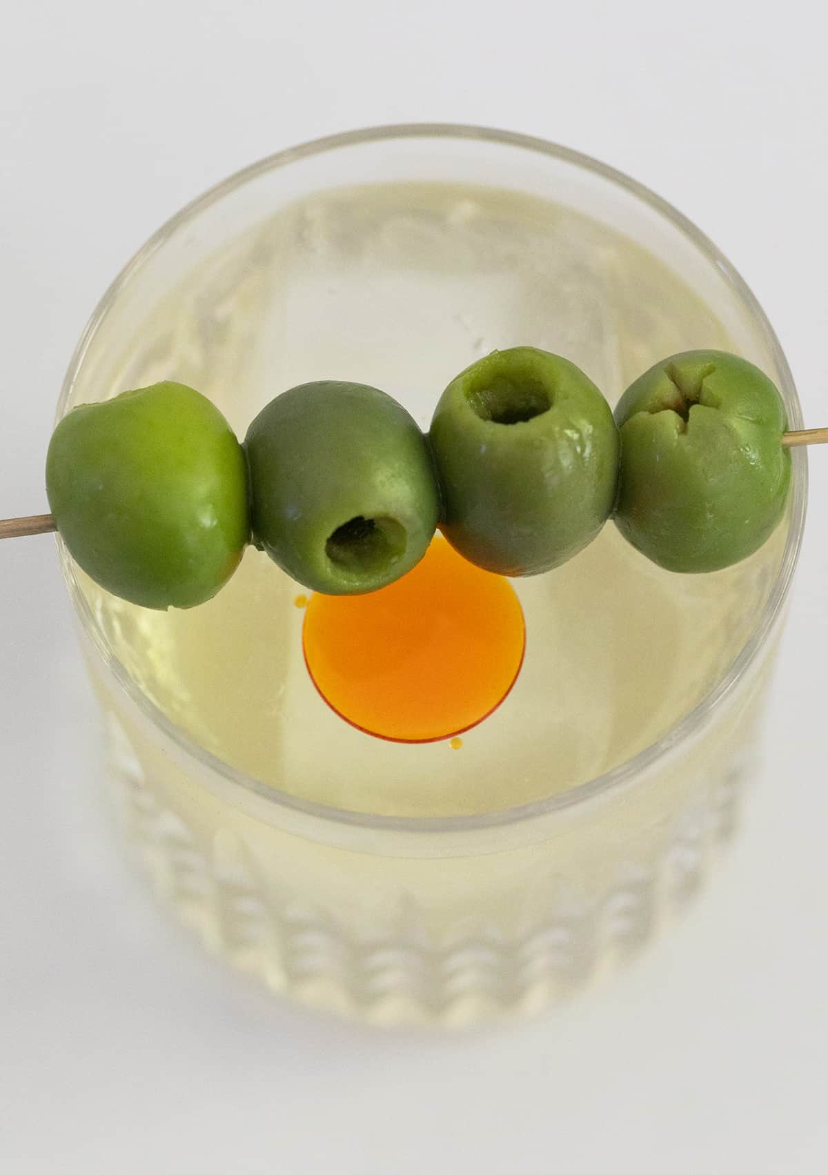 Green olives sitting over a dirty martini 