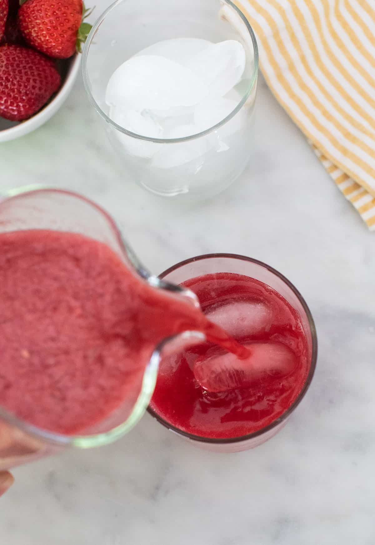 Pouring berry lemonade into a glass