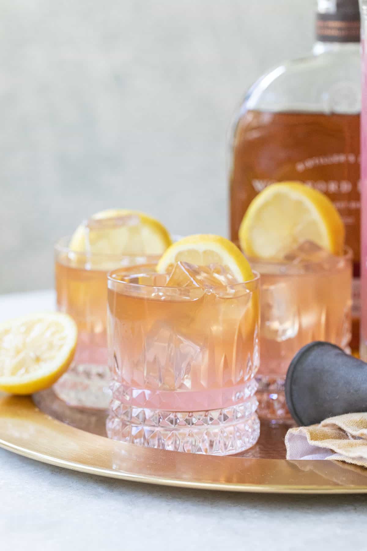 Whiskey and lemonade on a tray with lemon.