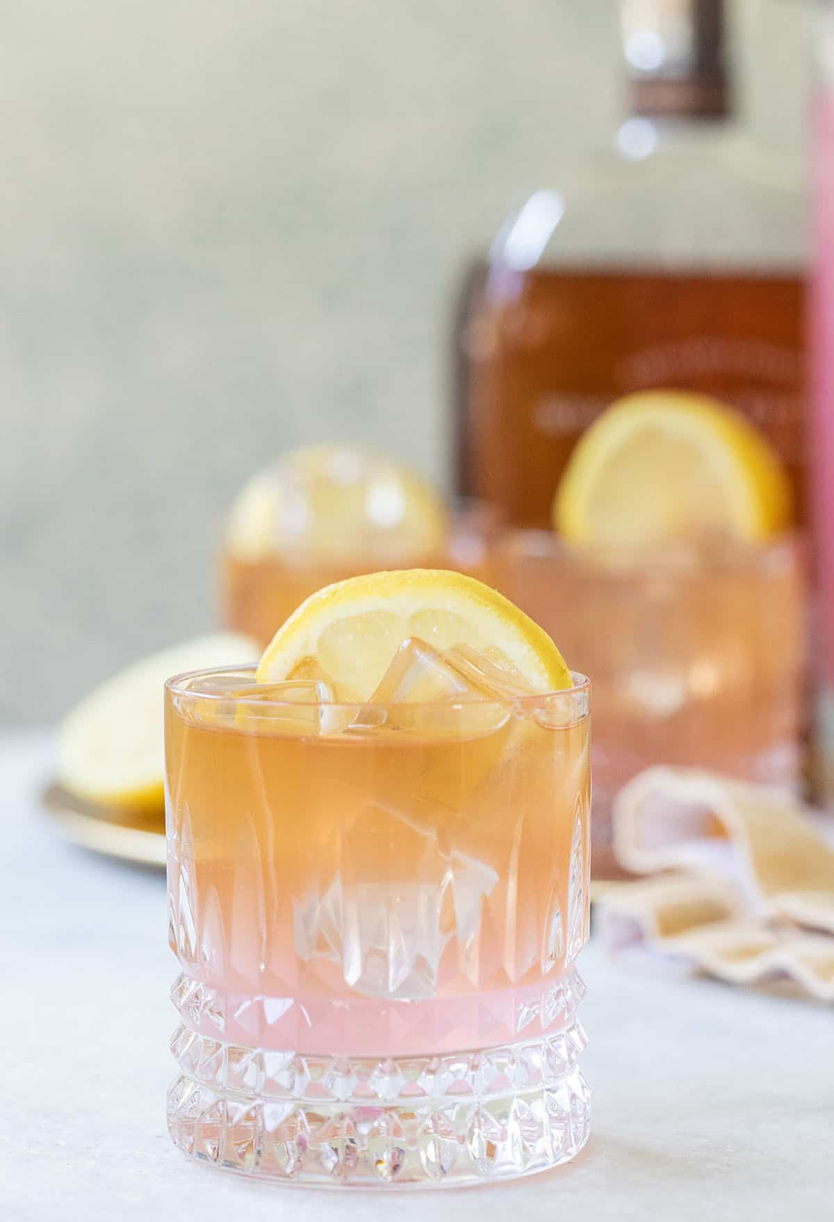 Whiskey lemonade made with pink lemonade and garnished with a lemon wheel.