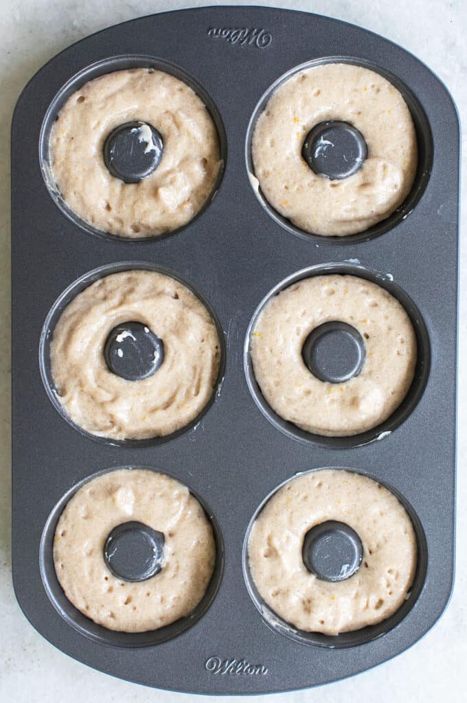 Appel cider donut batter in a donut pan before baking.