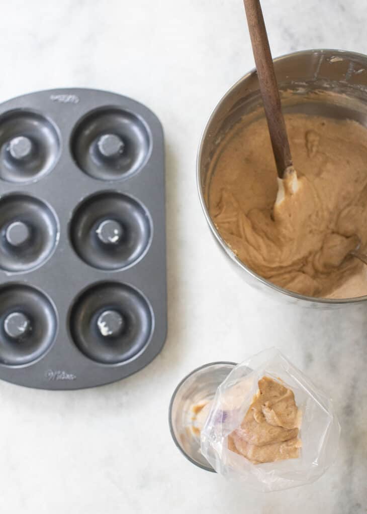 Donut batter, donut pan and a bowl of donut batter on a table.