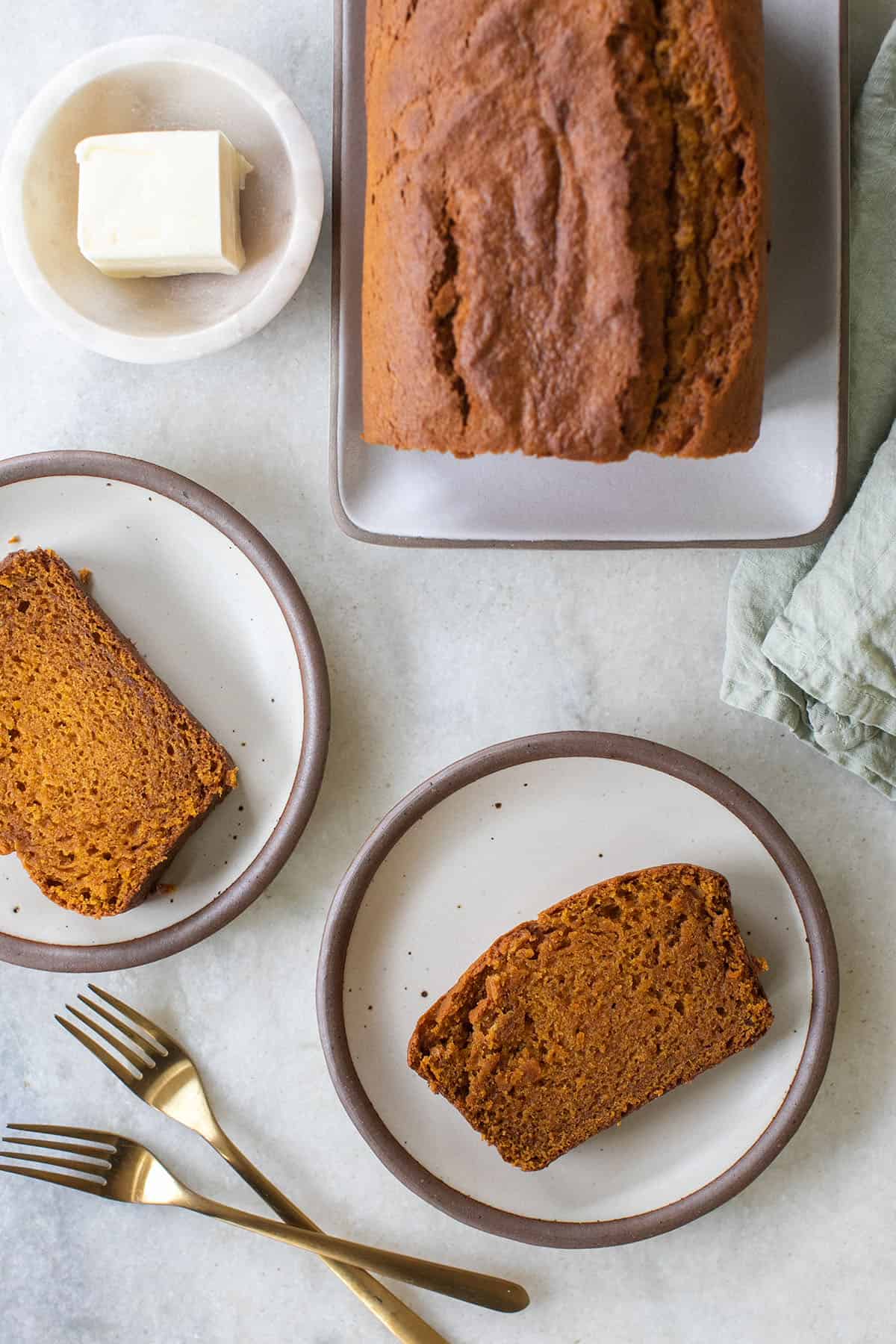 Easy pumpkin bread, sliced on the table with butter.