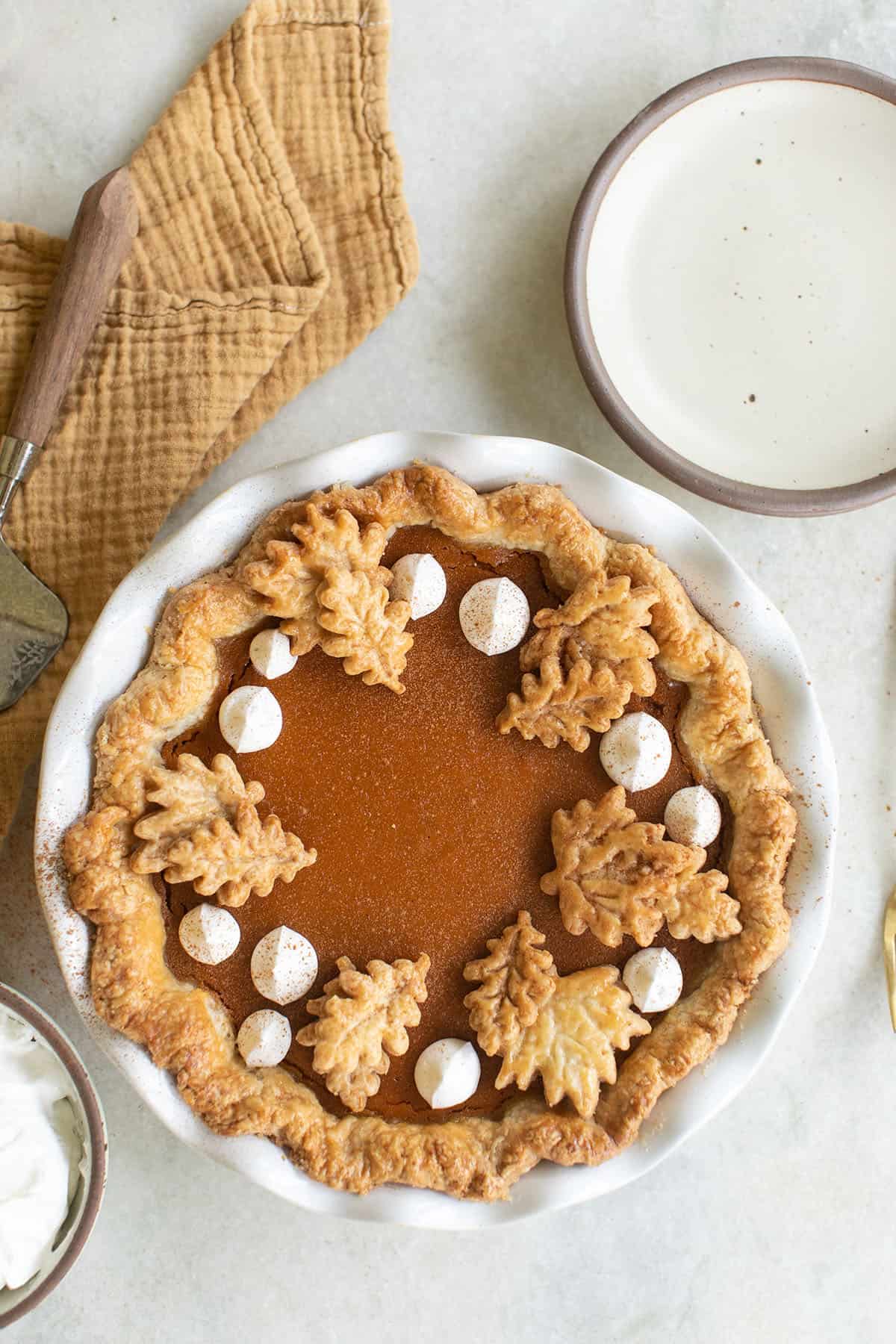 Sweet potato pie on a table with whipped cream.