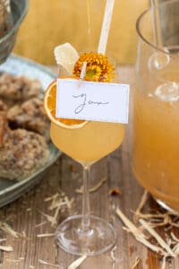 Apple cider cocktail in a wine glass with a name card.