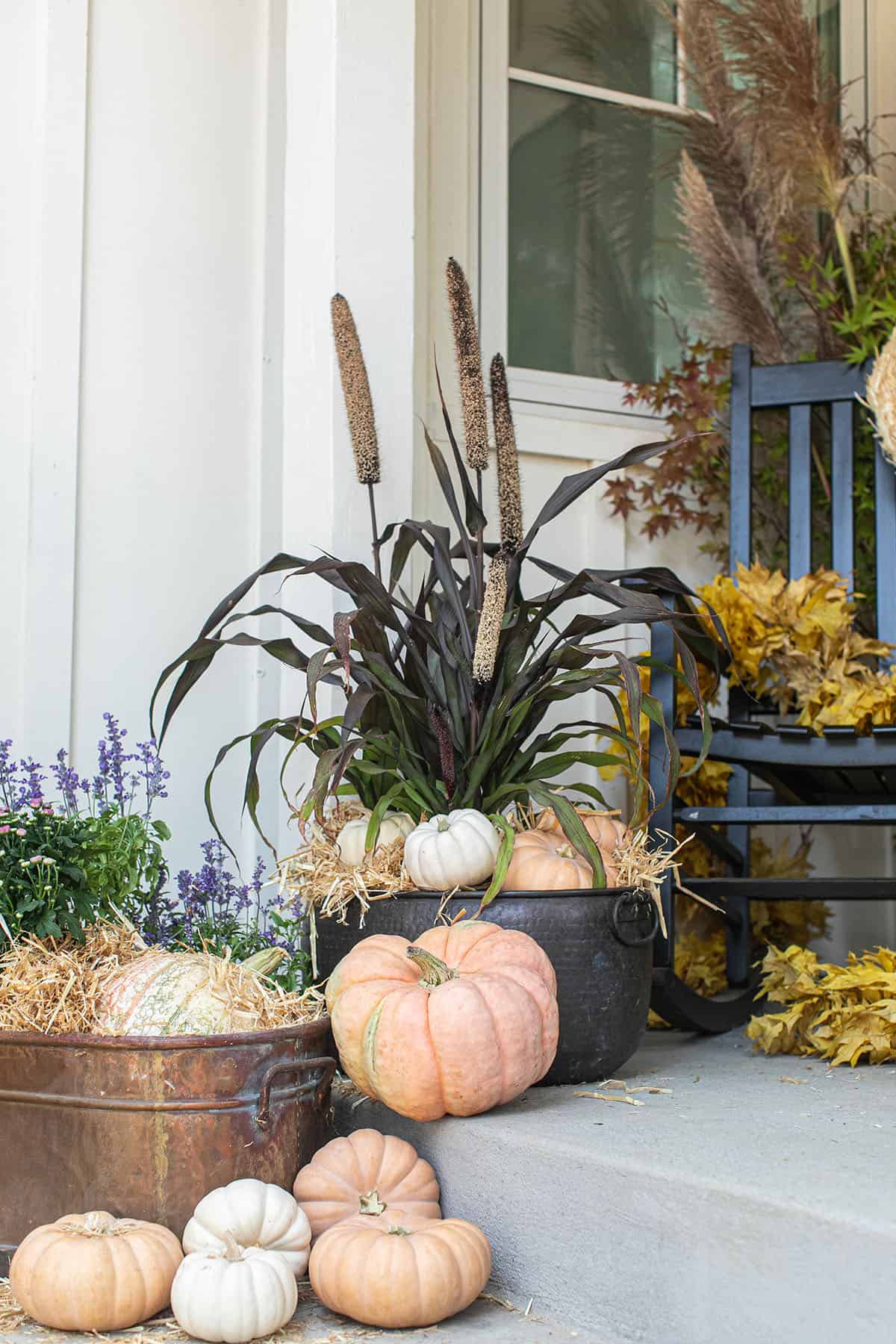 Fall porch decor with unique pumpkins and flowers in copper pots.