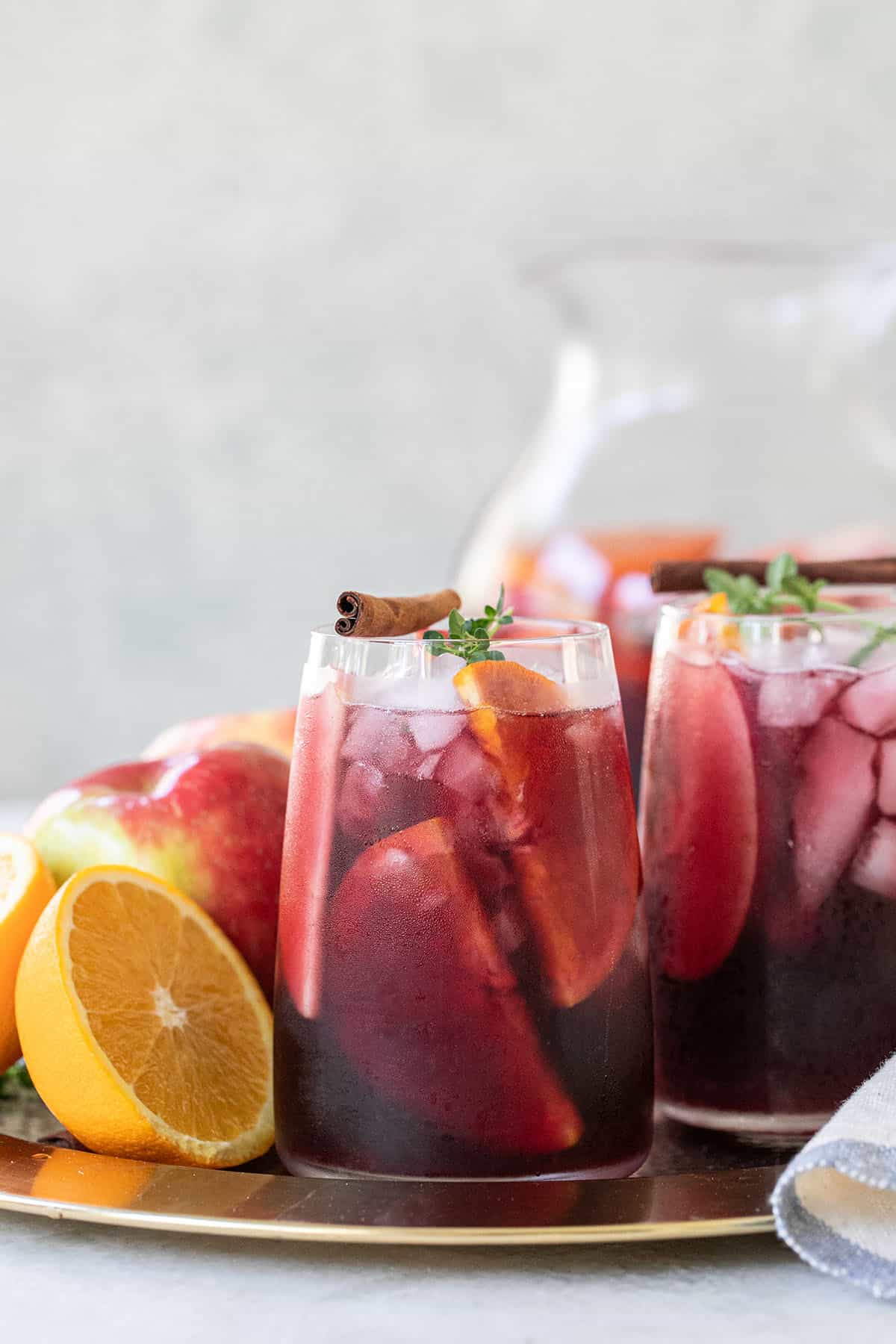 Fall sangria in a glass with cinnamon, thyme and an orange slice.