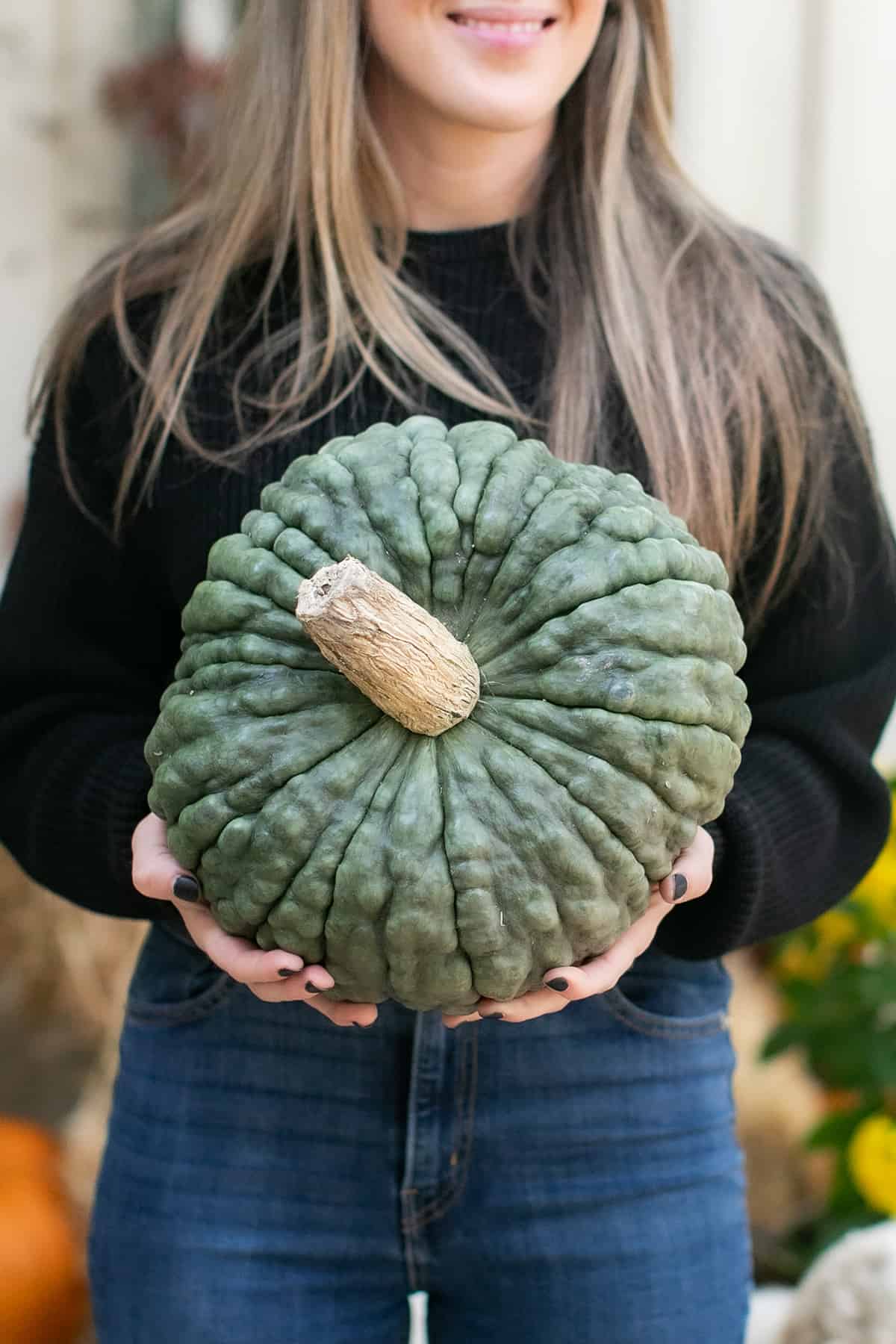 Eden Passante holding a green pumpkin.