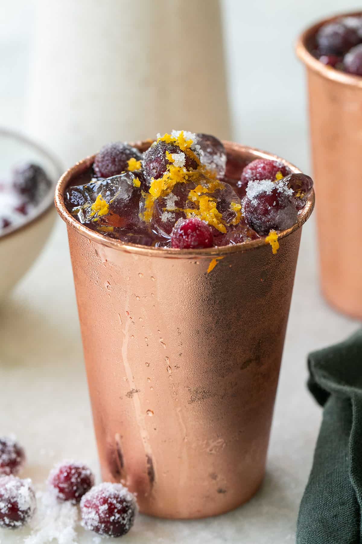 Cranberry cocktail in a copper cup with sugared cranberries.