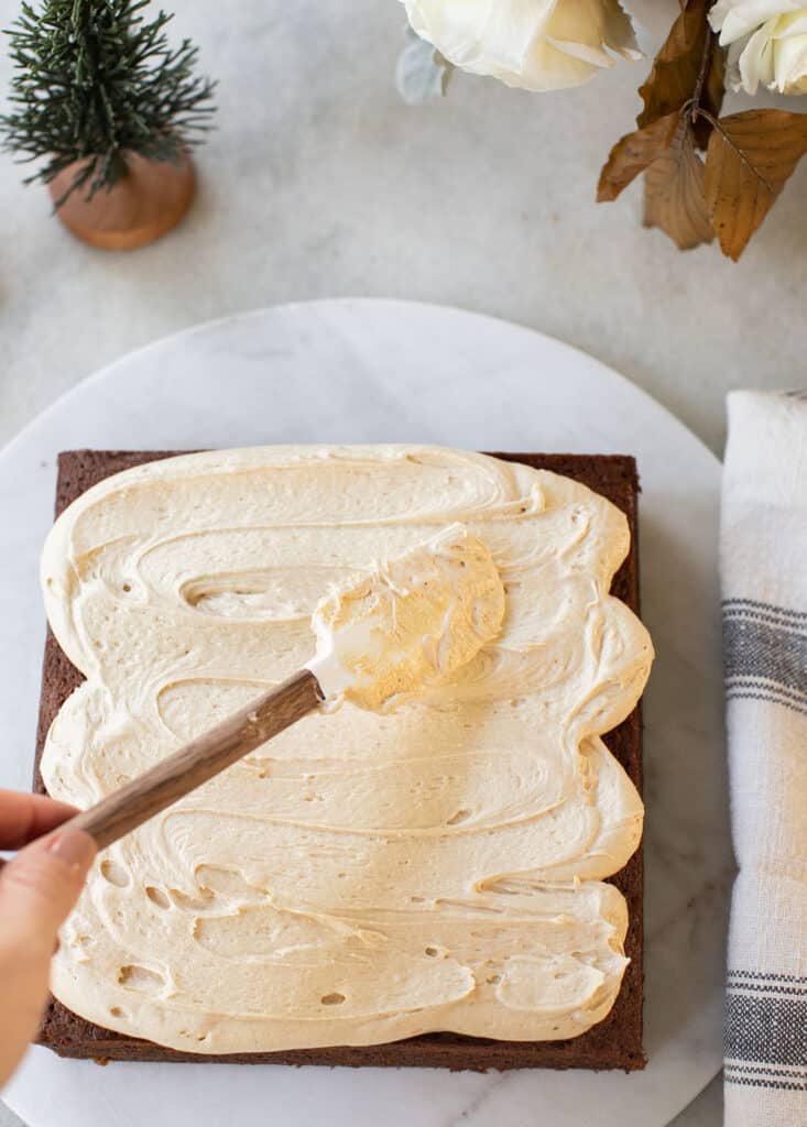 Spreading gingerbread buttercream over a cooled gingerbread cake.