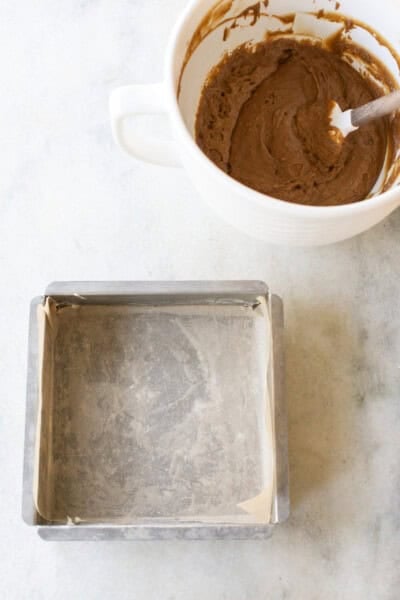 A prepared cake pan and gingerbread cake batter in a bowl.