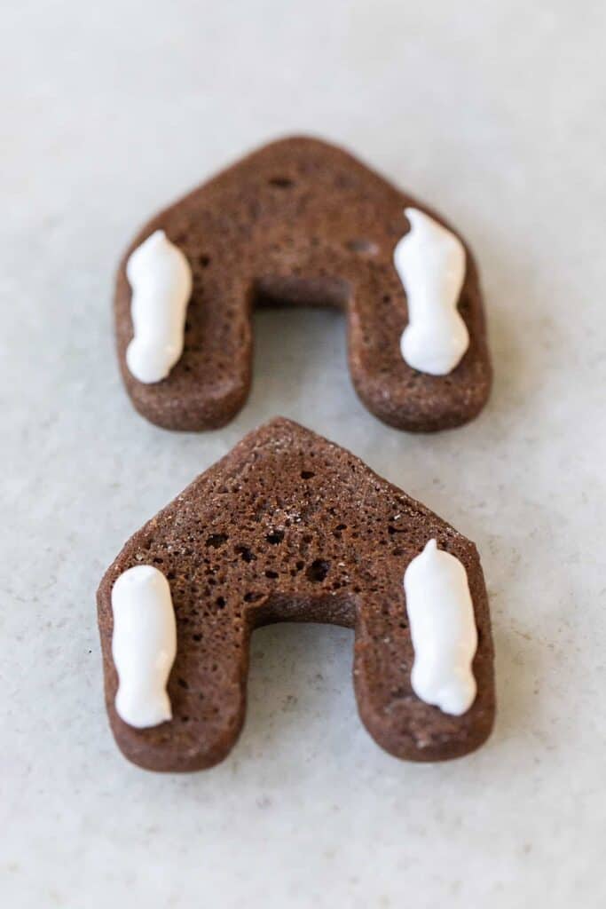 Adding icing on two mini gingerbread houses.