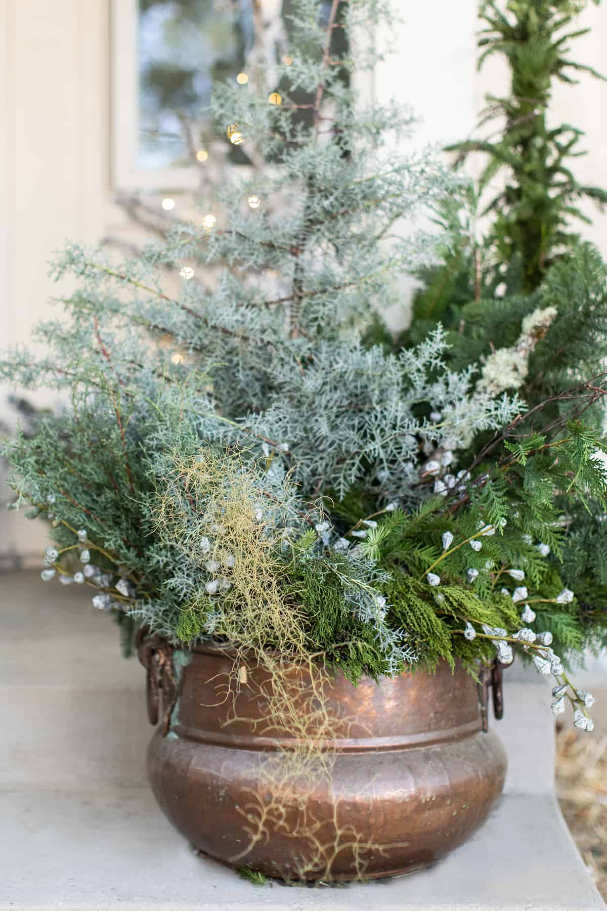 outdoor Christmas decorations in a copper pot.