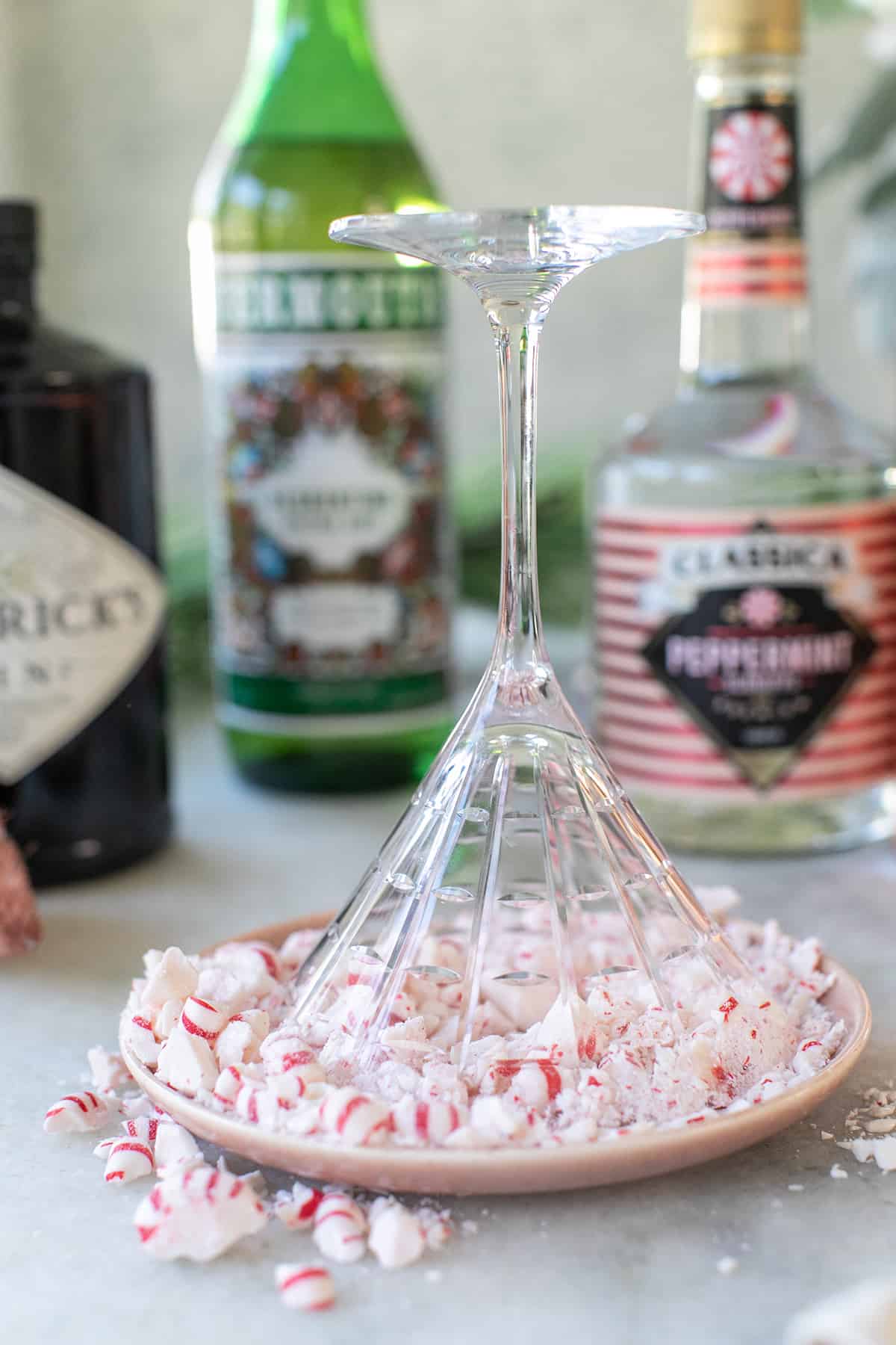 Riming a martini glass glass with crushed candy canes - chocolate peppermint martini, crushed peppermint, peppermint candies.