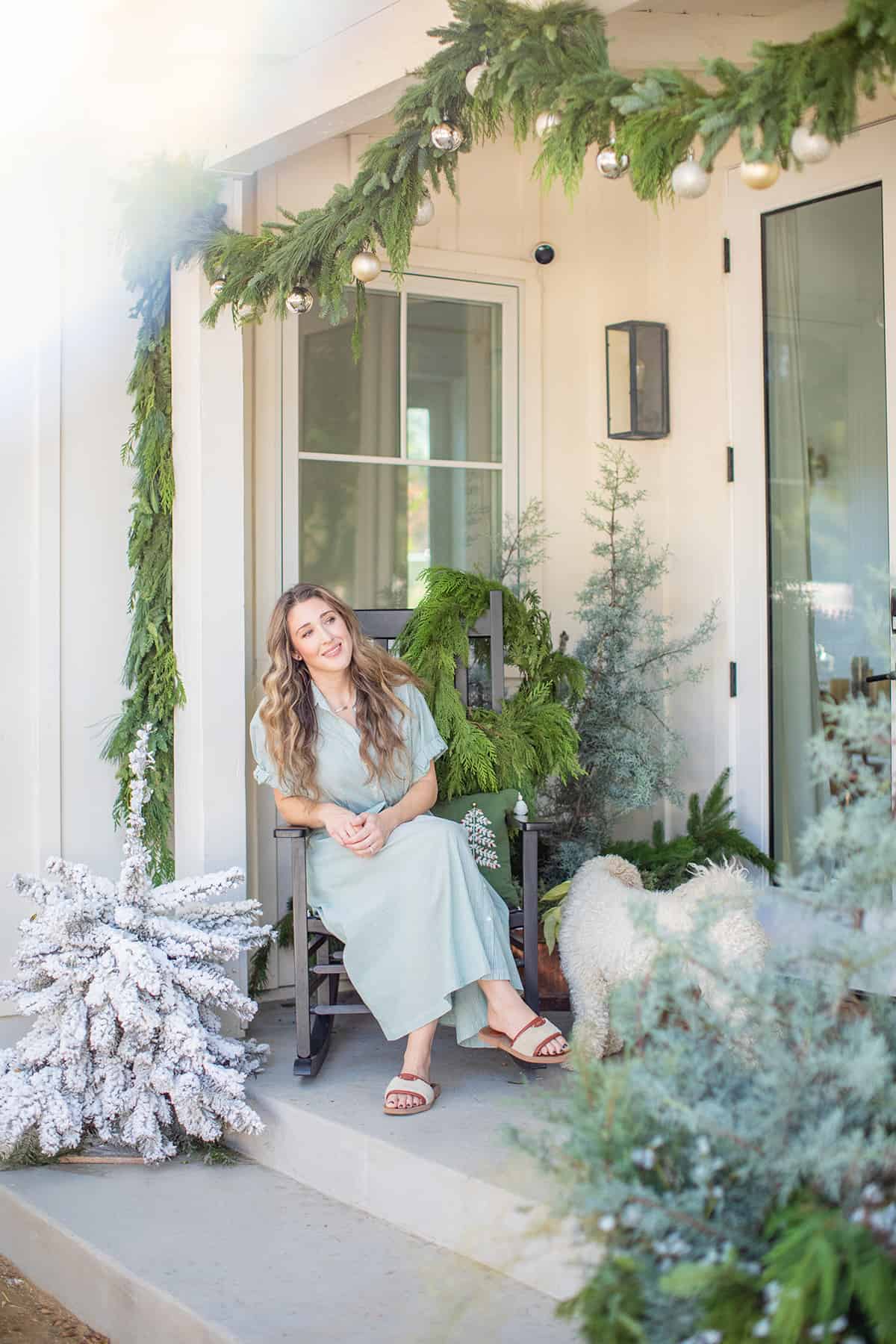 Eden Passante sitting on a rocking chair on her decorated  Christmas porch.