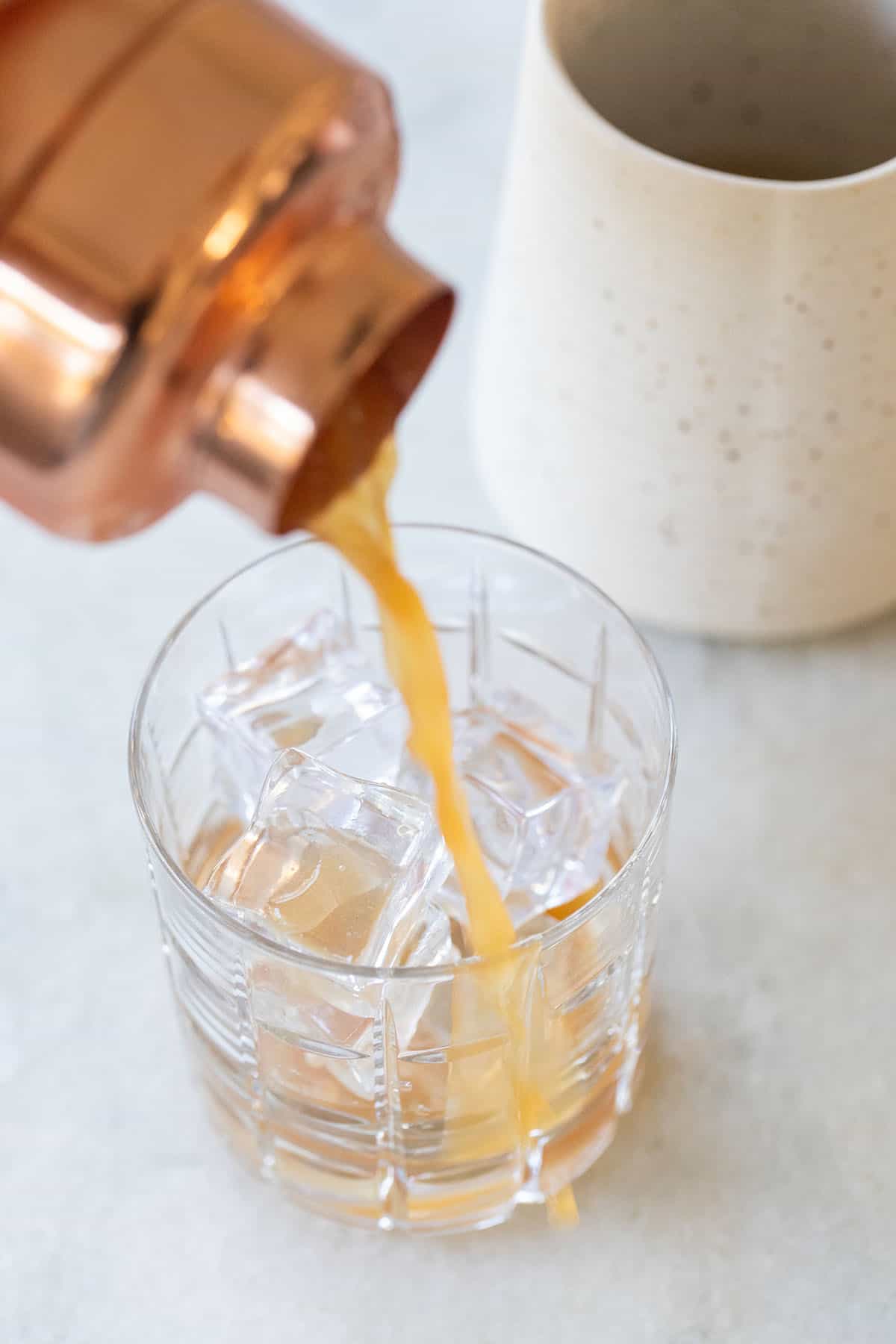 pouring a grapefruit cocktail into a glass