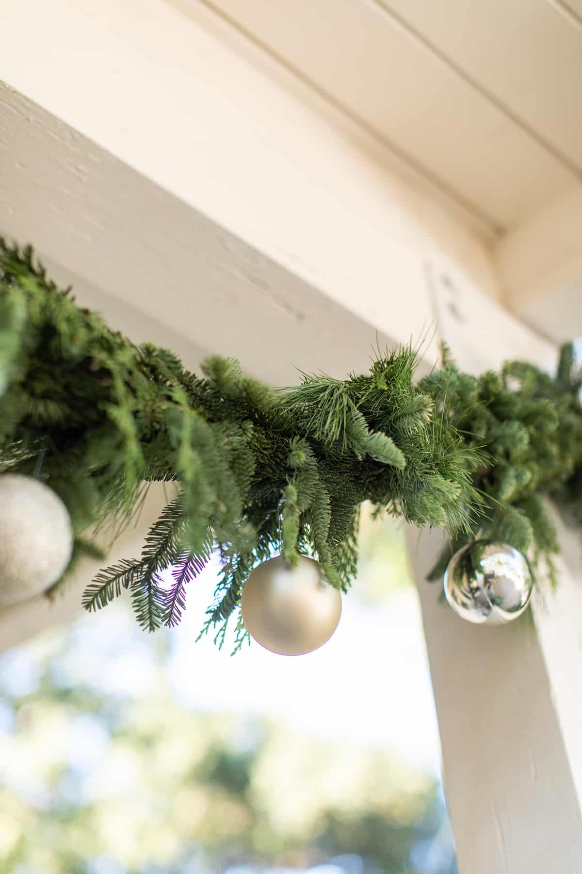 garland and ornaments in fresh garland hanging on a front porch.